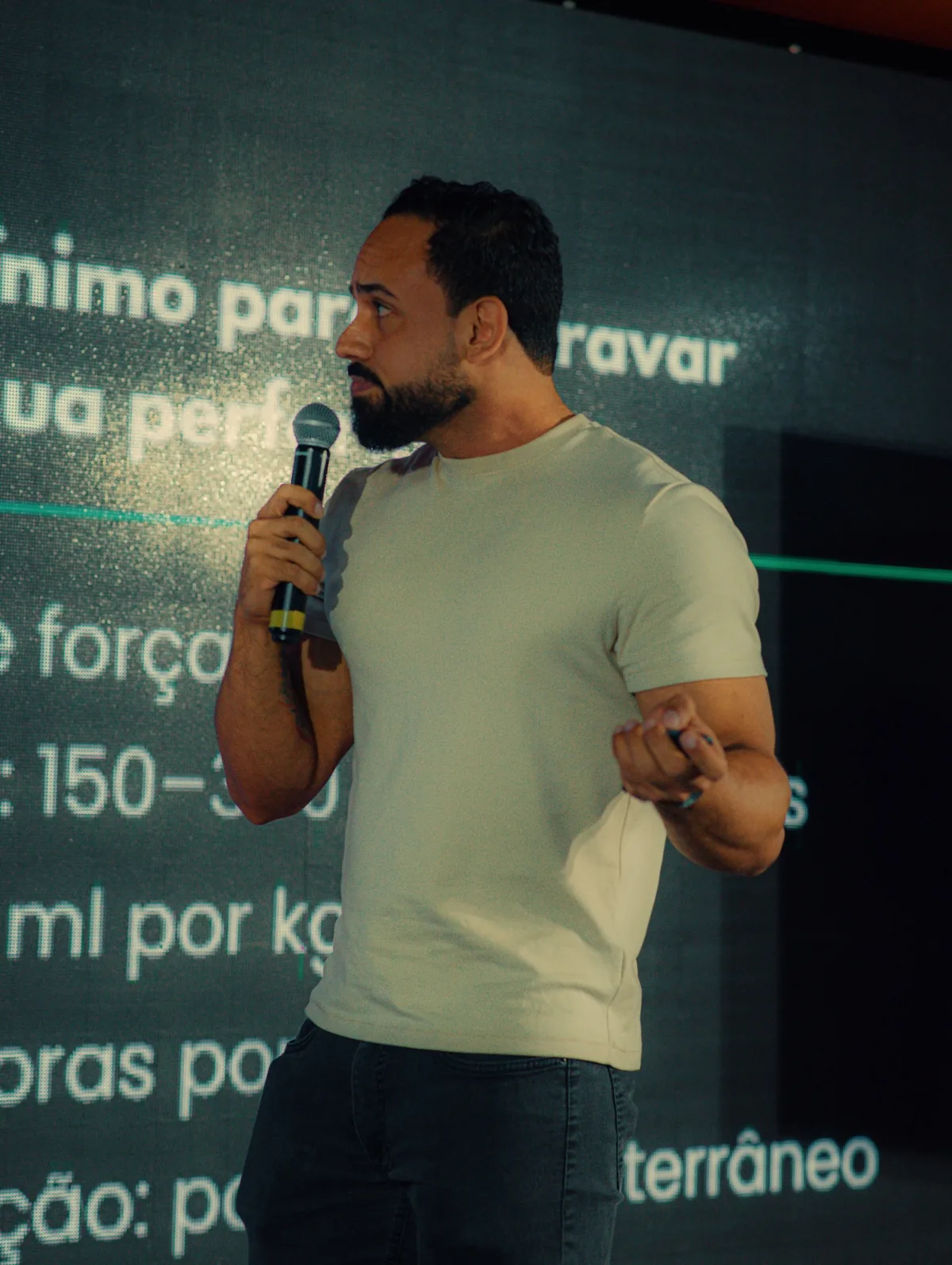Franthesco Curbani palestrando ao microfone diante de um telão