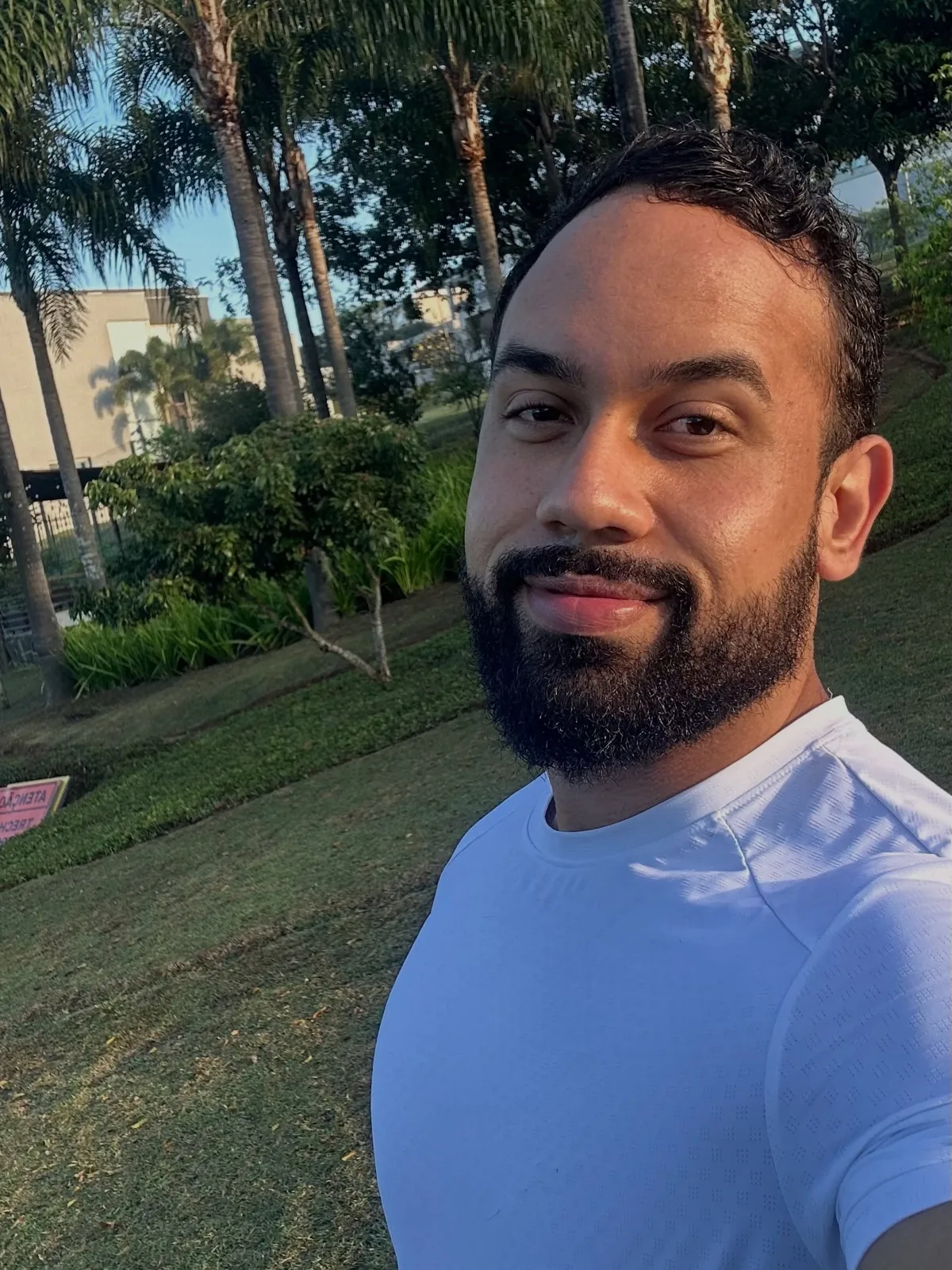 Franthesco Curbani sorrindo em selfie ao ar livre, camiseta azul clara
