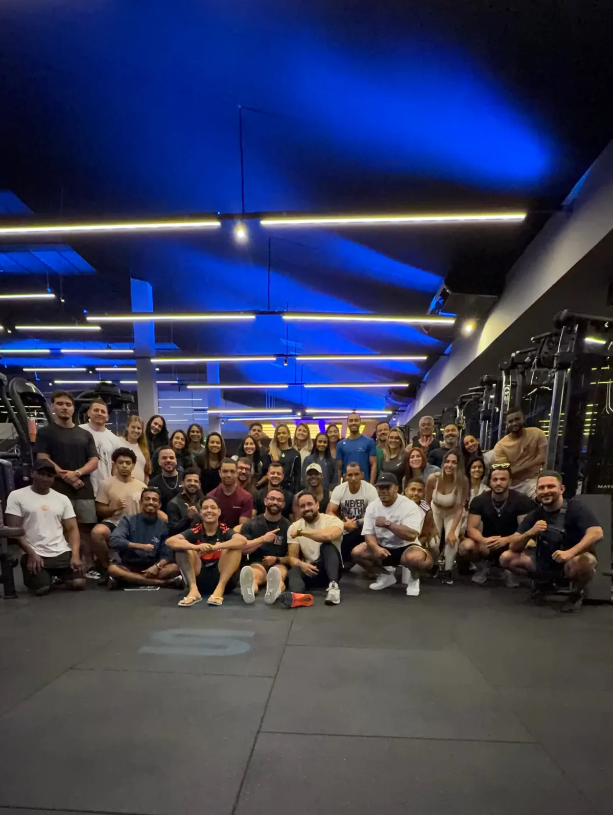 Turma de 40 profissionais sentada no chão da academia em um domingo de curso
