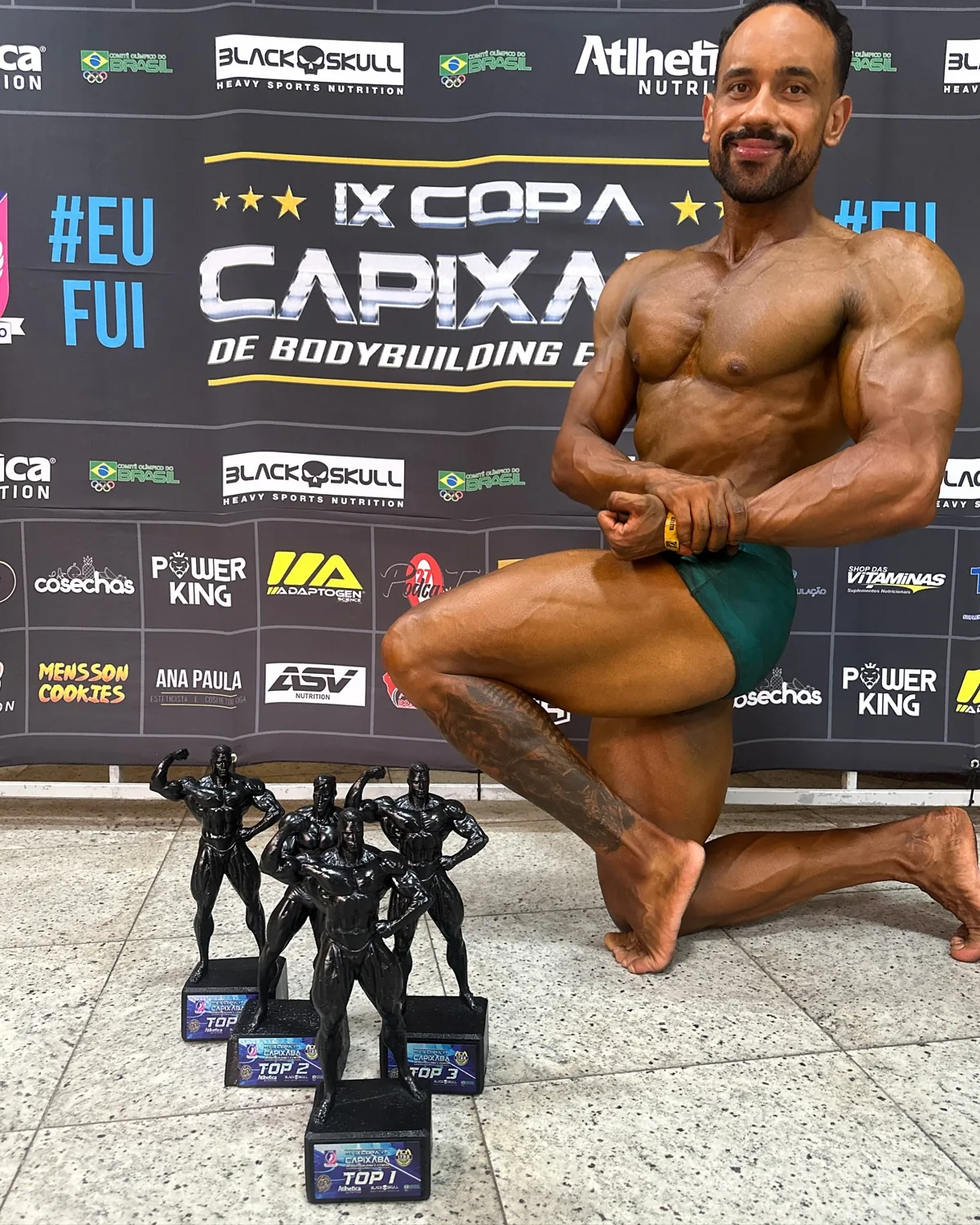Franthesco Curbani no palco da IX Copa Capixaba de bodybuilding com troféus